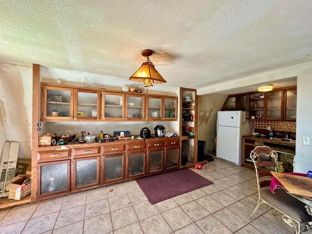 kitchen featuring a textured ceiling, light tile patterned floors, and white refrigerator