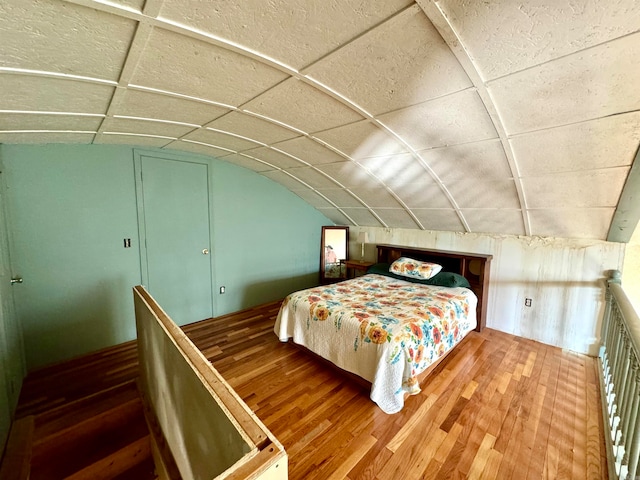 bedroom with wood-type flooring, a drop ceiling, and vaulted ceiling