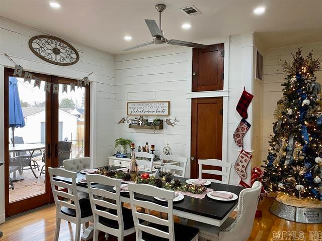 dining space featuring wood walls, ceiling fan, and light hardwood / wood-style flooring