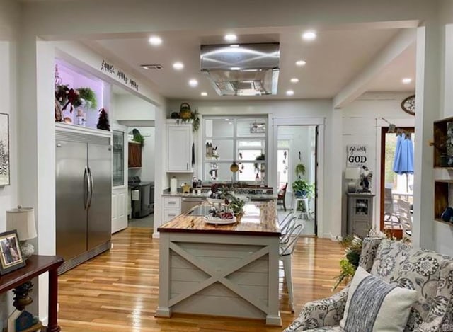 kitchen with light hardwood / wood-style flooring, white cabinetry, built in refrigerator, and stove