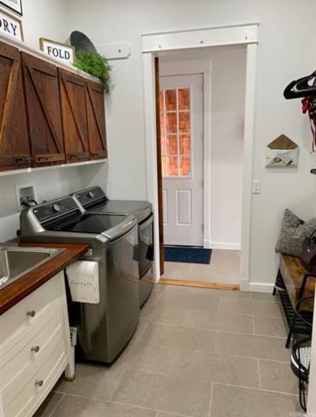 laundry room featuring separate washer and dryer, cabinets, and light tile patterned floors