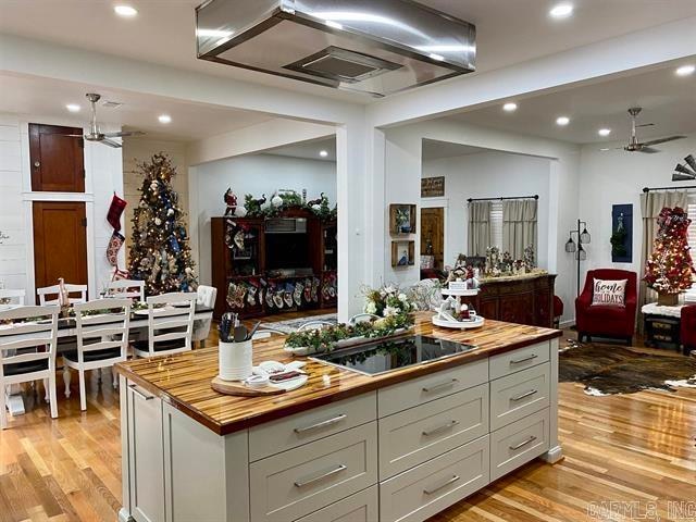 kitchen with black electric cooktop, light wood-type flooring, butcher block countertops, and a center island