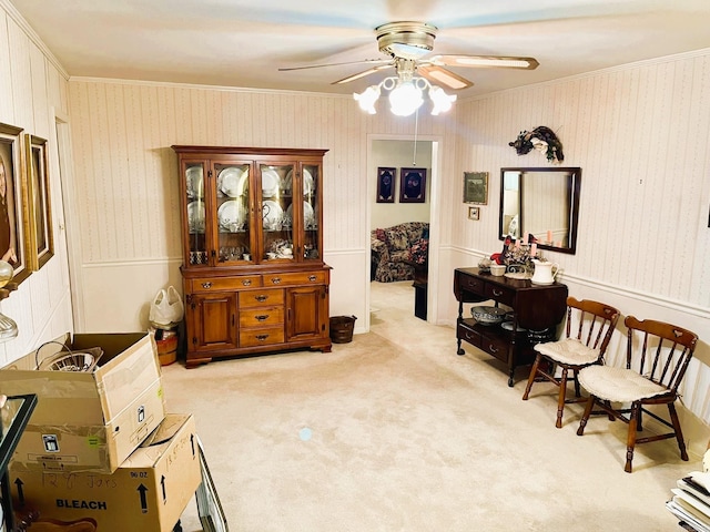 living area with ornamental molding, light carpet, and ceiling fan