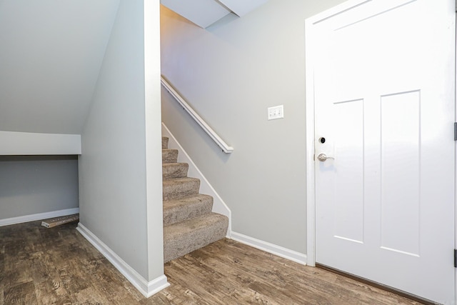 stairs with vaulted ceiling and hardwood / wood-style floors