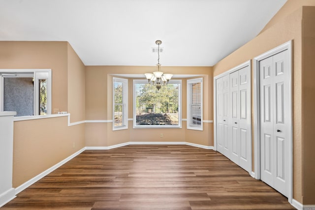 unfurnished dining area featuring wood-type flooring and an inviting chandelier