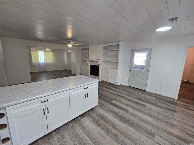 kitchen with wood-type flooring, white cabinets, and light stone counters