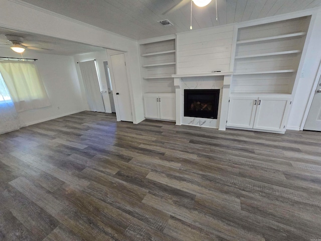 unfurnished living room featuring ceiling fan, a fireplace, dark wood-type flooring, and built in features