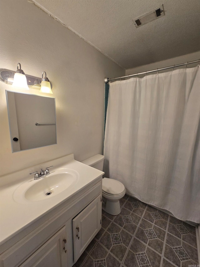 bathroom featuring a textured ceiling, vanity, toilet, and tile patterned floors