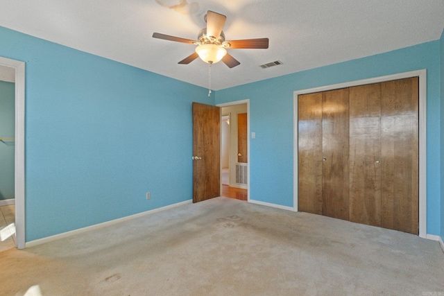 unfurnished bedroom featuring a closet, ceiling fan, and light colored carpet