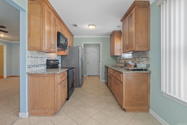 kitchen featuring light stone countertops, sink, crown molding, decorative backsplash, and black appliances