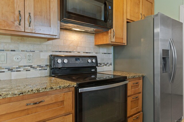 kitchen with black appliances, light stone counters, and backsplash