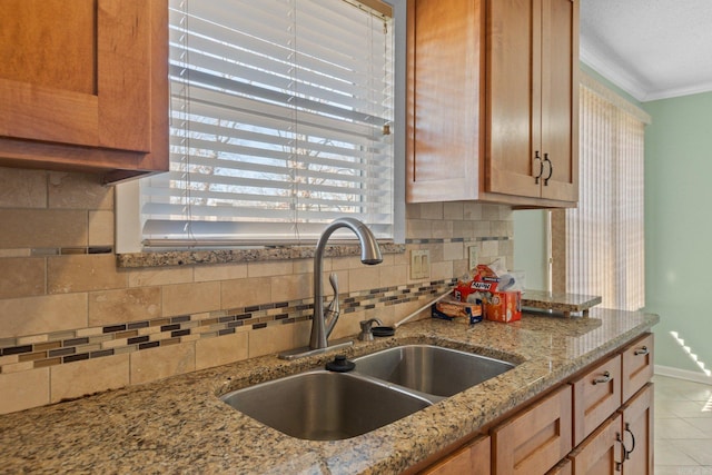 kitchen featuring light stone countertops, sink, tasteful backsplash, light tile patterned floors, and ornamental molding