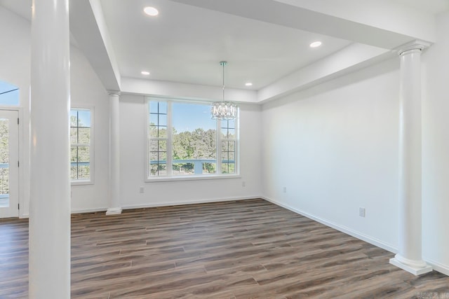 unfurnished dining area with ornate columns, a chandelier, and dark hardwood / wood-style flooring