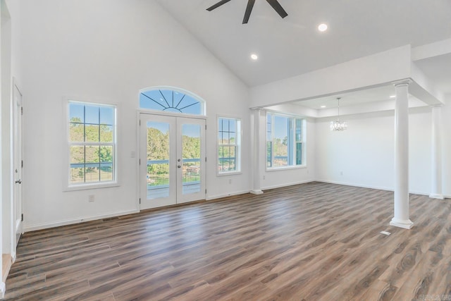 unfurnished living room featuring high vaulted ceiling, ceiling fan with notable chandelier, a healthy amount of sunlight, and dark hardwood / wood-style flooring