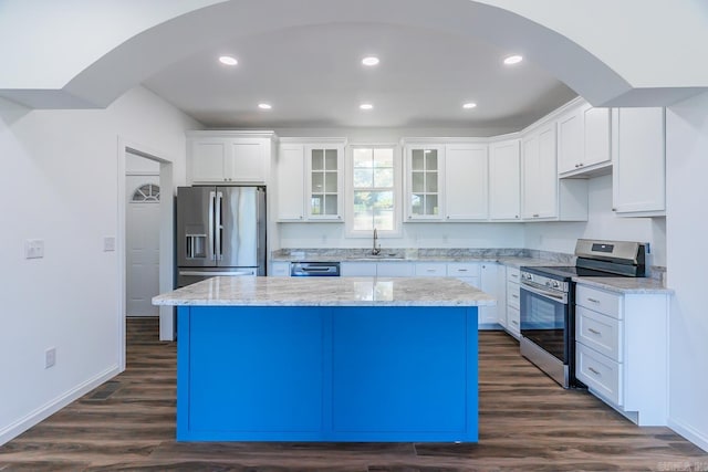 kitchen featuring appliances with stainless steel finishes, white cabinetry, a center island, dark hardwood / wood-style floors, and sink