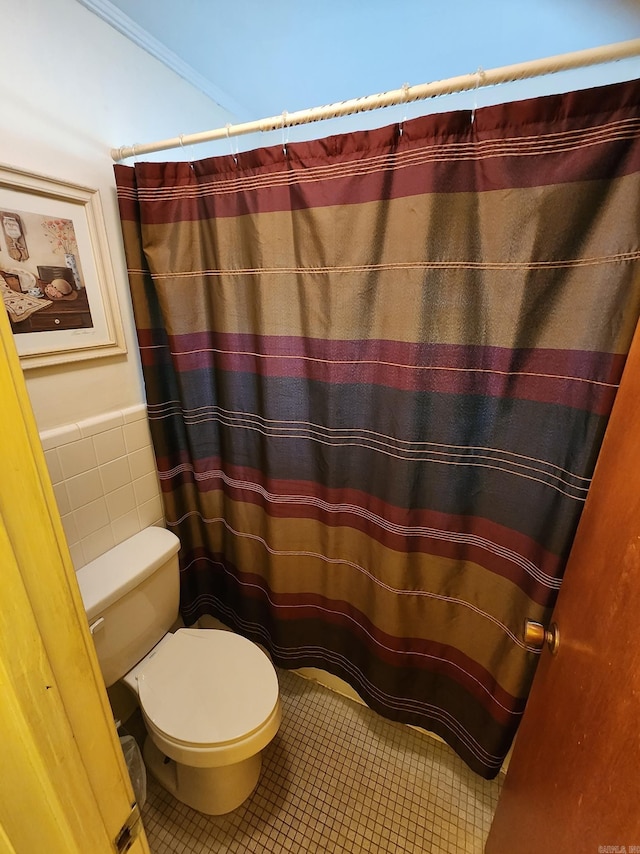 bathroom featuring tile walls, tile patterned flooring, and toilet