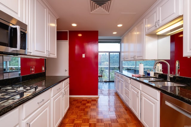 kitchen featuring stainless steel appliances, dark stone countertops, and white cabinetry