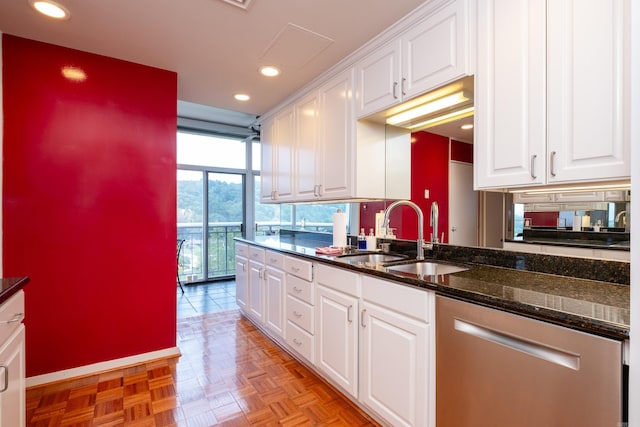 kitchen with dark stone counters, light parquet floors, sink, white cabinets, and stainless steel dishwasher