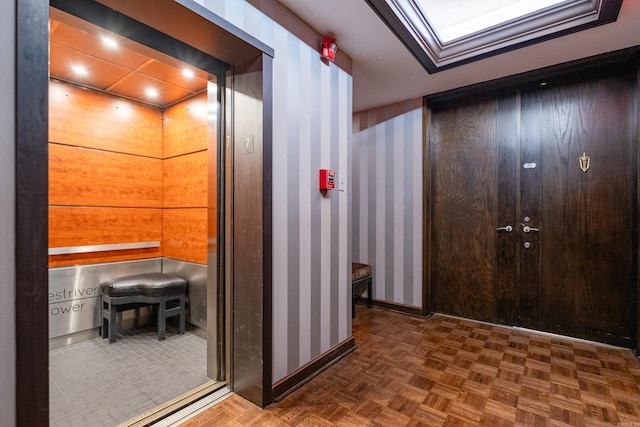 hallway with wooden walls and dark parquet flooring