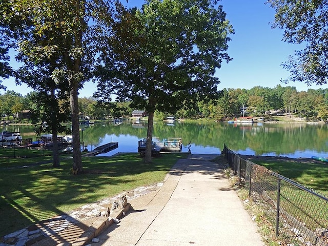 view of dock with a water view and a lawn