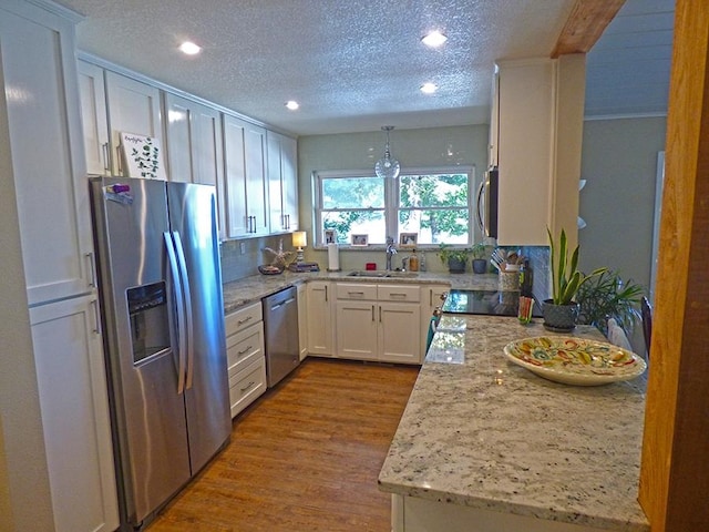 kitchen with sink, tasteful backsplash, white cabinetry, hardwood / wood-style flooring, and stainless steel appliances