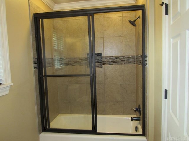 bathroom featuring bath / shower combo with glass door and crown molding