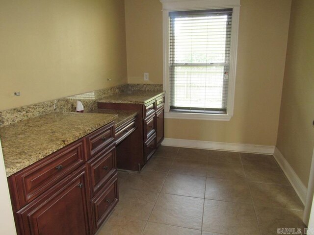 201 W Palm, Lonoke, AR 72086 - kitchen featuring light tile patterned flooring, baseboards, light stone countertops, and reddish brown cabinets