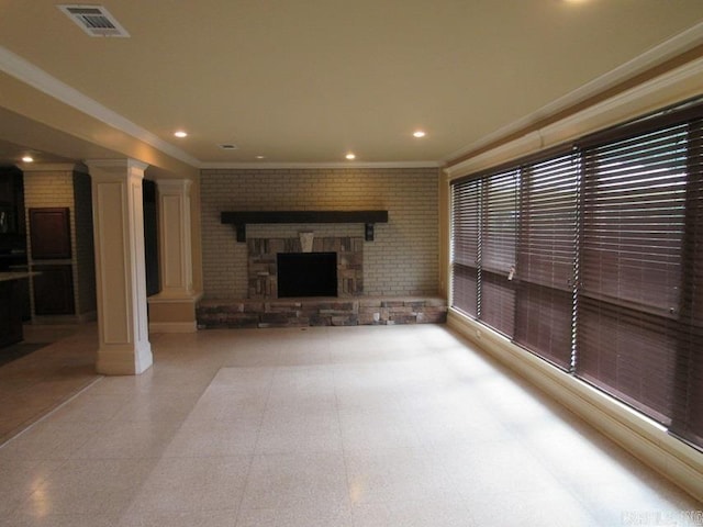 unfurnished living room with brick wall, a fireplace, crown molding, and decorative columns