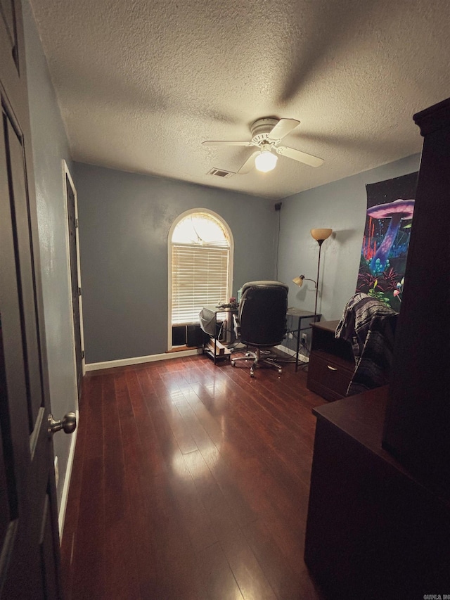 office space featuring dark wood-type flooring, ceiling fan, and a textured ceiling