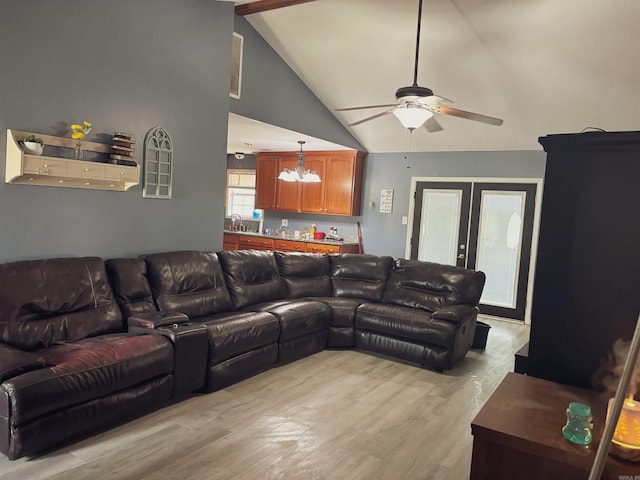 living room with high vaulted ceiling, french doors, sink, ceiling fan with notable chandelier, and light hardwood / wood-style flooring