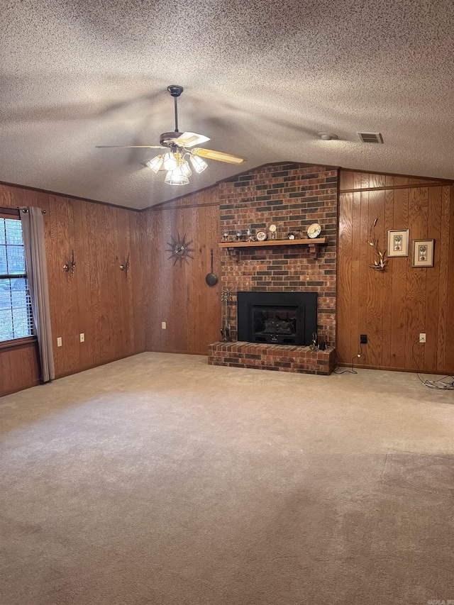 unfurnished living room with carpet, ceiling fan, wood walls, and a brick fireplace