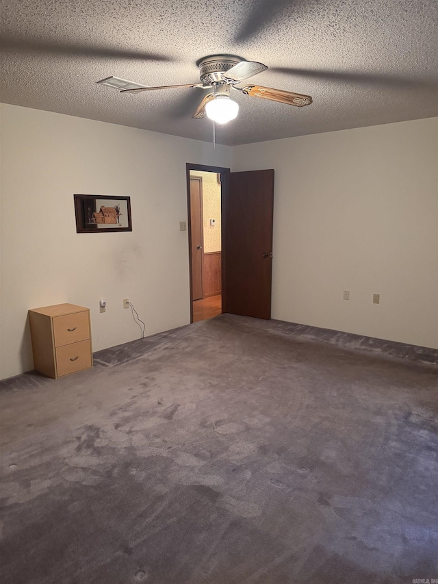 empty room featuring ceiling fan, carpet floors, and a textured ceiling