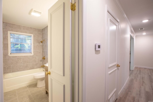 bathroom with tiled shower / bath combo, hardwood / wood-style floors, and toilet