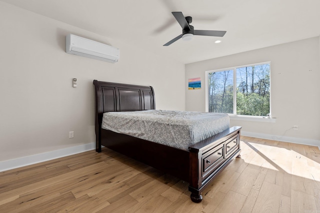 bedroom with light hardwood / wood-style floors, a wall unit AC, and ceiling fan