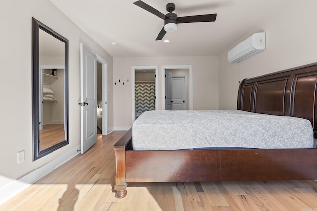 bedroom with light hardwood / wood-style floors, a wall unit AC, and ceiling fan