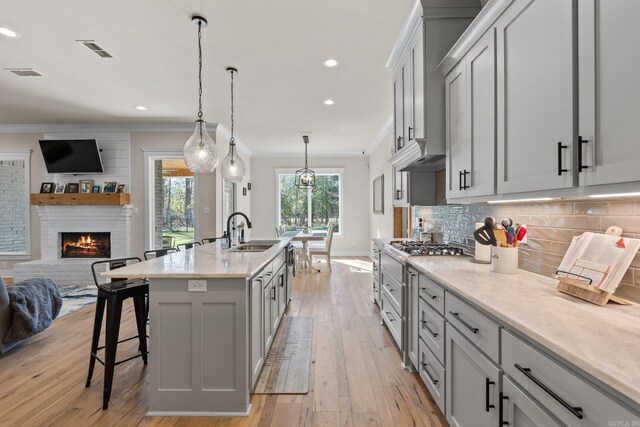 kitchen featuring light stone countertops, light hardwood / wood-style flooring, a fireplace, and sink