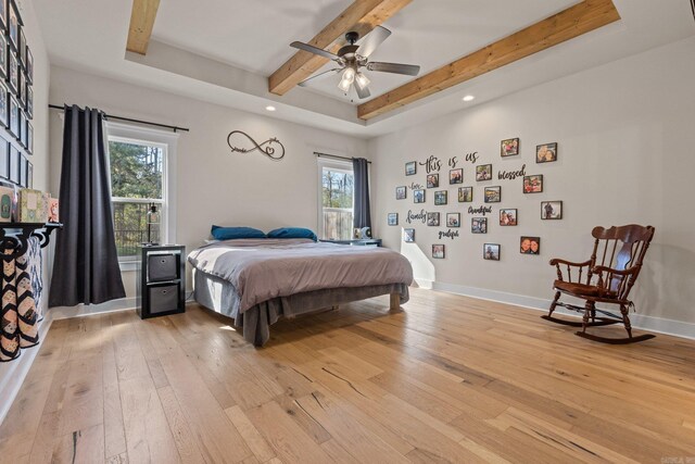 bedroom featuring ceiling fan, beamed ceiling, light hardwood / wood-style floors, and multiple windows