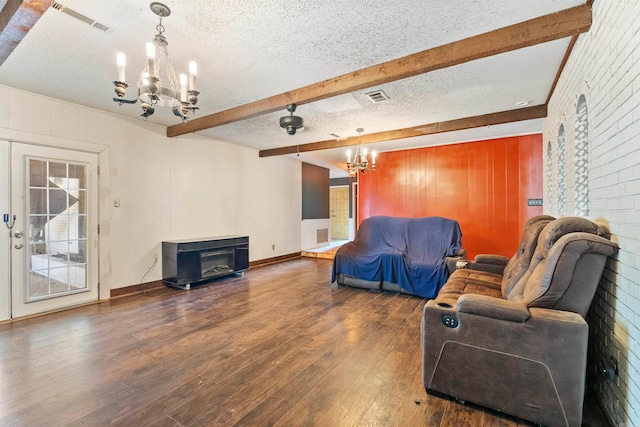 living room featuring an inviting chandelier, beamed ceiling, dark hardwood / wood-style floors, and a textured ceiling