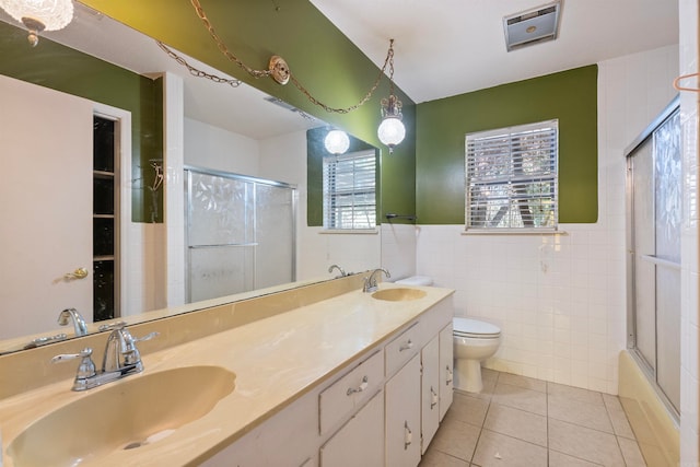 full bathroom featuring tile patterned flooring, enclosed tub / shower combo, toilet, tile walls, and vanity