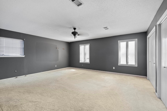 unfurnished room featuring ceiling fan, a textured ceiling, and light carpet