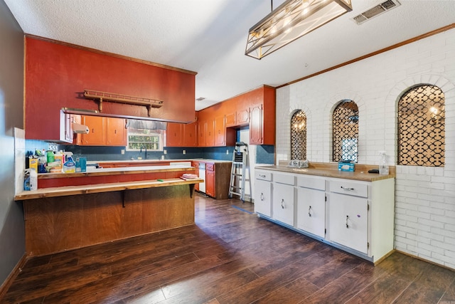 kitchen with brick wall, ornamental molding, dark hardwood / wood-style floors, and kitchen peninsula