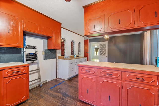 kitchen featuring ornamental molding, tasteful backsplash, a textured ceiling, dark wood-type flooring, and tile countertops