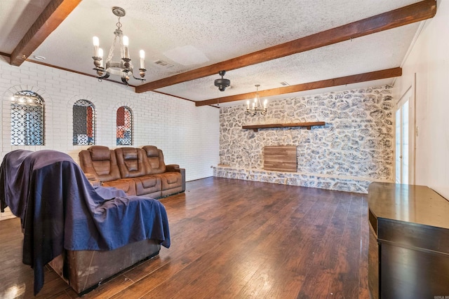 living room with beamed ceiling, a chandelier, dark wood-type flooring, brick wall, and a textured ceiling