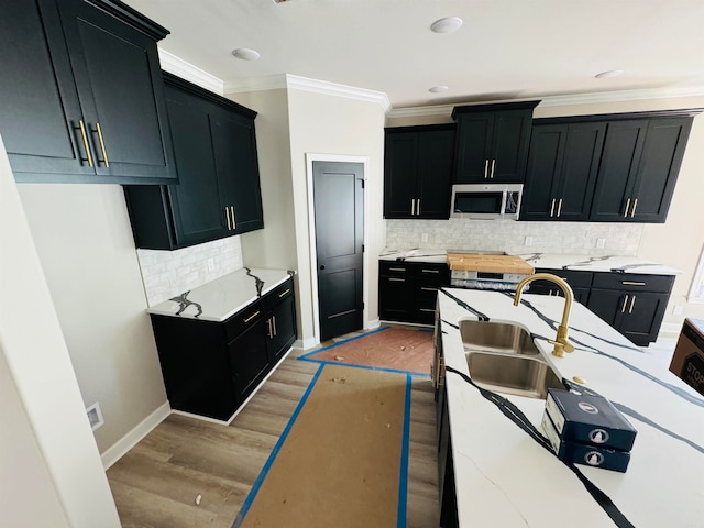 kitchen featuring sink, light wood-type flooring, light stone countertops, stainless steel appliances, and ornamental molding