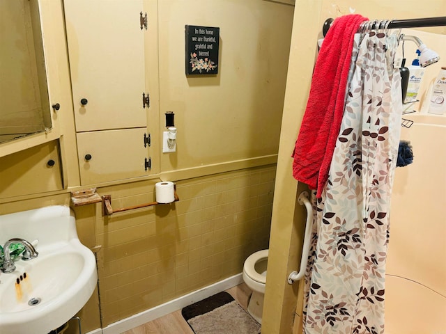 bathroom with toilet, sink, tile walls, a shower with shower curtain, and hardwood / wood-style flooring