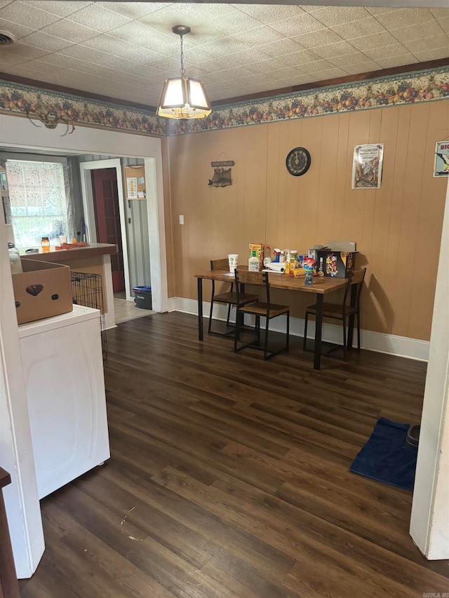 dining area featuring wooden walls, washer / clothes dryer, and dark hardwood / wood-style flooring