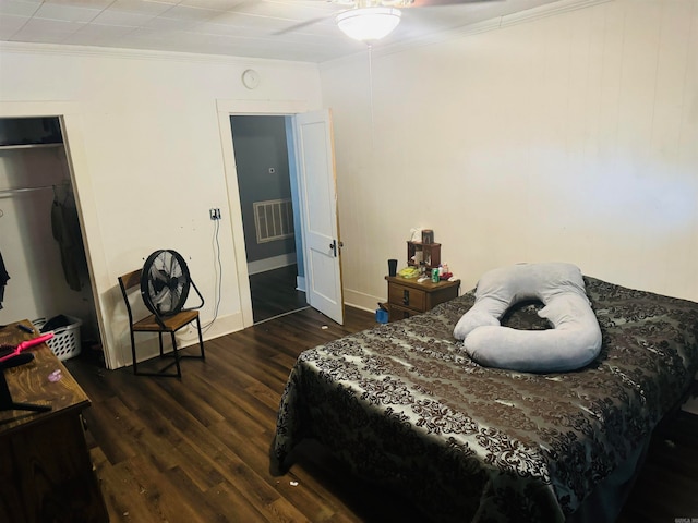 bedroom with a closet, dark hardwood / wood-style floors, and crown molding