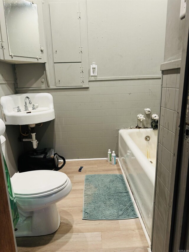 805 Clifton St, Camden, AR 71701 - full bath featuring wood finished floors, a tub, wainscoting, tile walls, and a sink