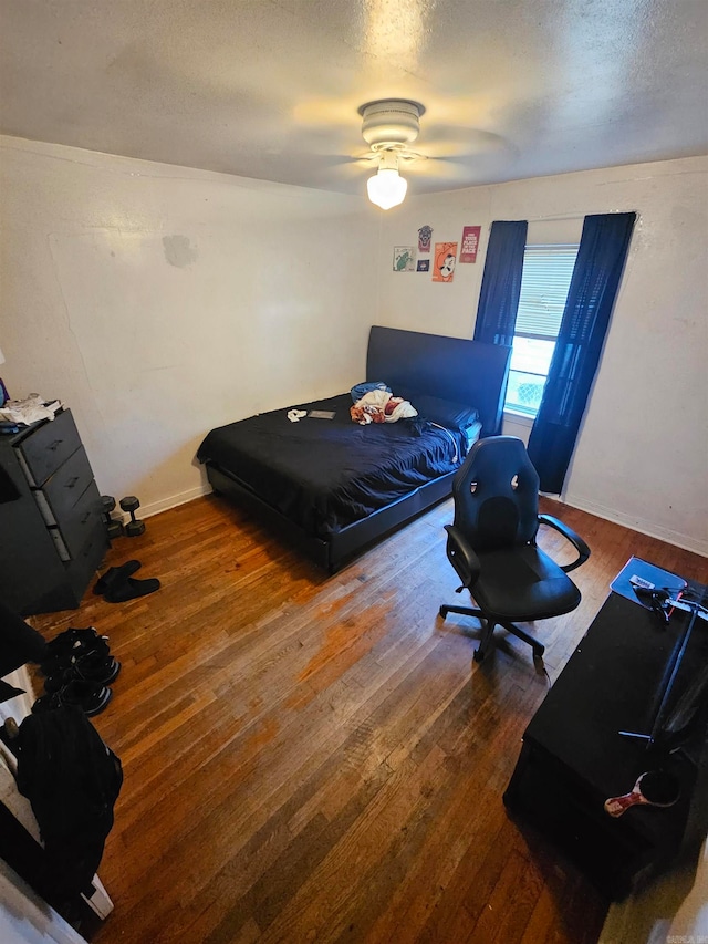 bedroom featuring hardwood / wood-style floors, a textured ceiling, and ceiling fan