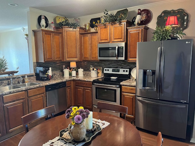 kitchen with appliances with stainless steel finishes, sink, ornamental molding, and dark hardwood / wood-style flooring